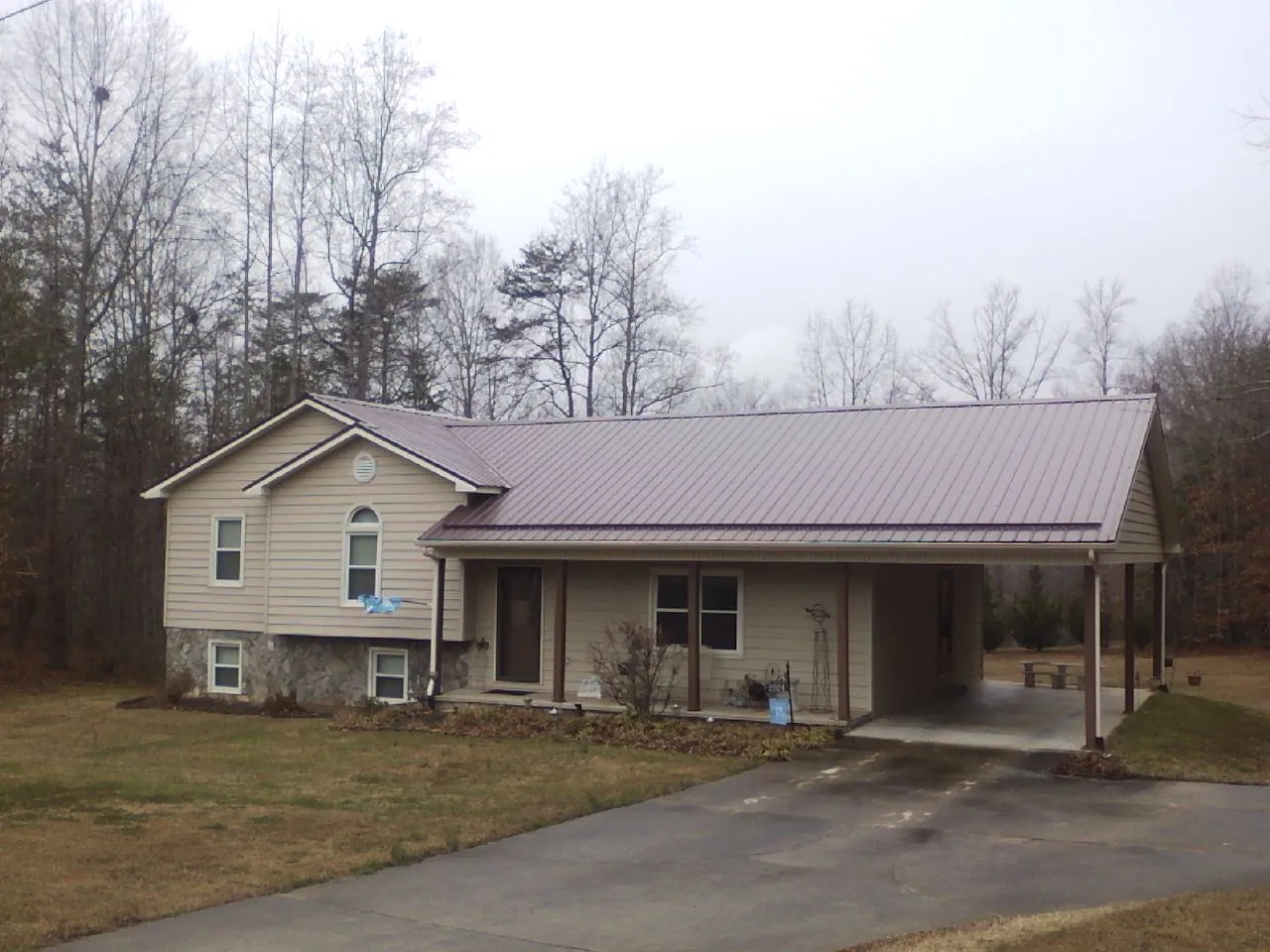 Burgundy metal roof on a tan split level home with an attached carport in Yulan