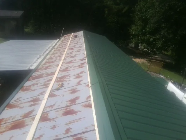 Old rusted panels beside newly installed green metal roofing — Wind Damage Roof Repair by Roofing Brothers in Yulan