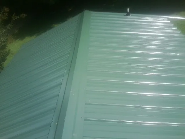 New green metal panels meeting at the ridge of a roof — Flat Roof Repair work by our crew in Yulan