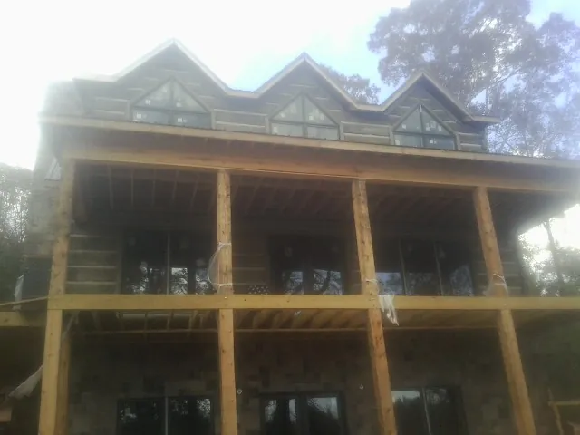 Dormers and porch framing on a large log home under construction — Roof Coating work by our crew in Yulan