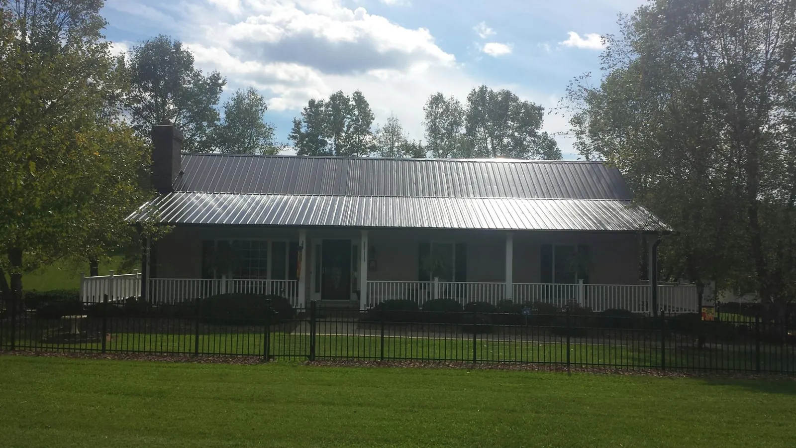 Gray metal roof on a brick ranch with a full width front porch — Gutter Guard Installation work by our crew in Yulan