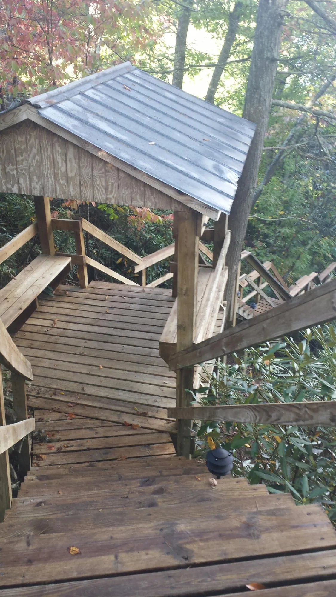 Metal roofed shelter over wooden steps on a wooded walkway — Skylight Repair & Installation work by our crew in Yulan