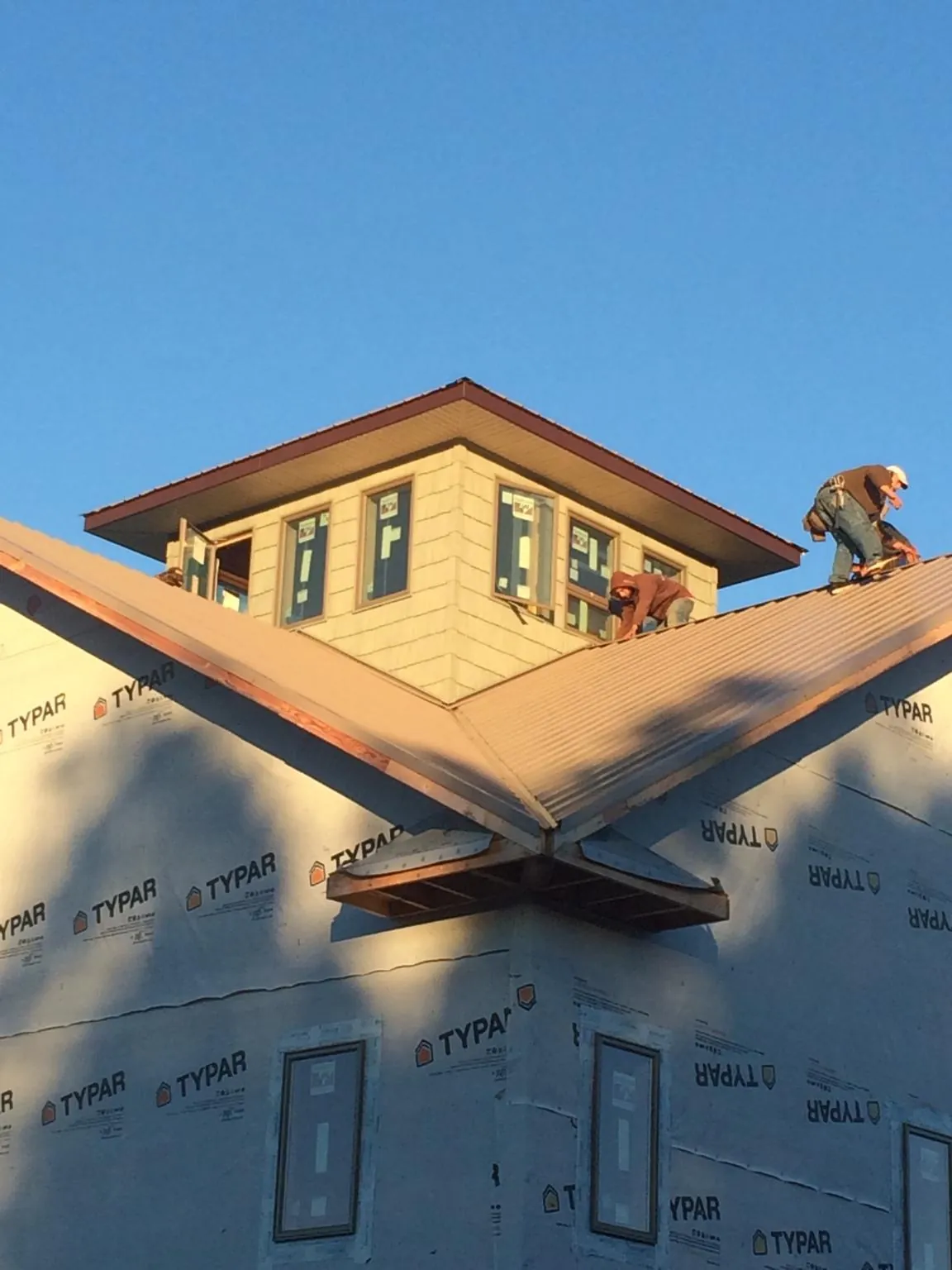 Roofers working around a rooftop cupola on a new metal roof at sunset — Roof Waterproofing in Yulan by Roofing Brothers
